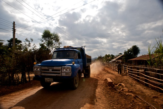 A truck rumbles by on a dirt road, near Phonsavan