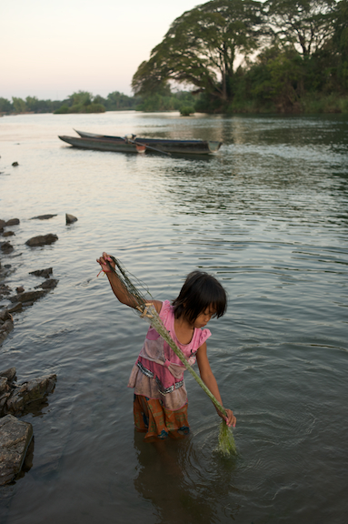 A young girl checks her net for fish in the Mekong