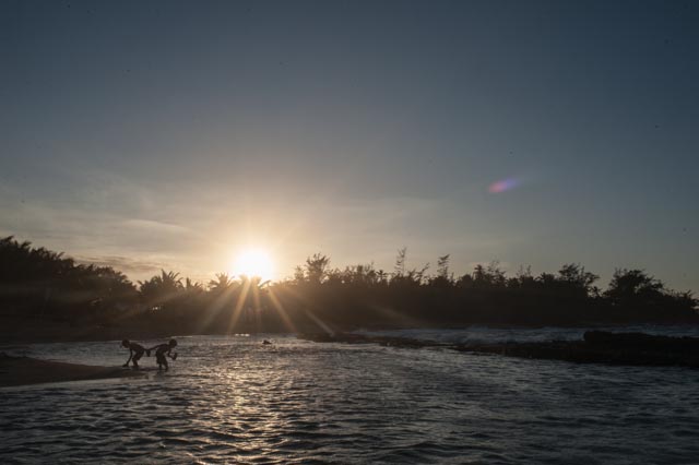 Children rinse off their sandals as they prepare to head home after an evening at the beach