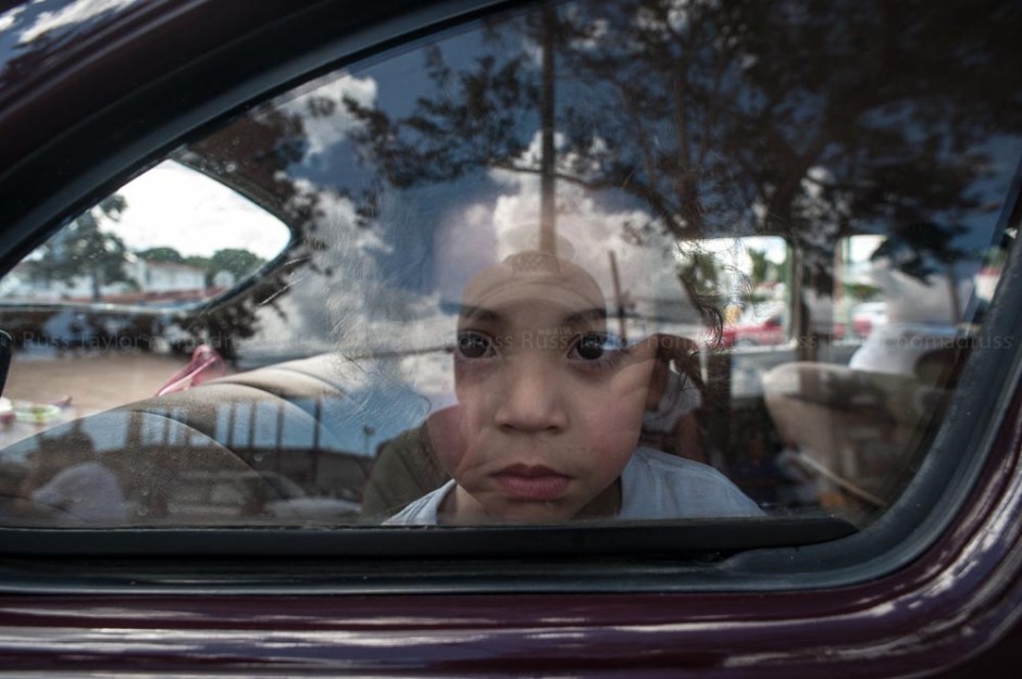 A young girl looks out the window of her family's car as it makes its way down the parade route